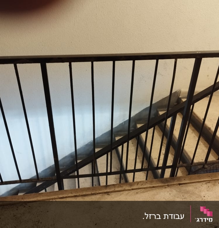 מעקה מתכת שחור על מדרגות בטון